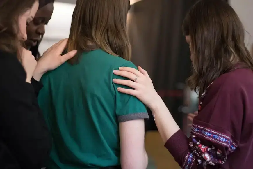 women praying together while laying hands on the shoulder