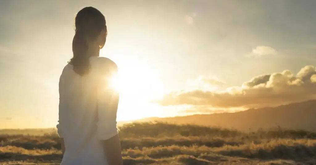 A woman looking far on the sunset or sunrise thinking
