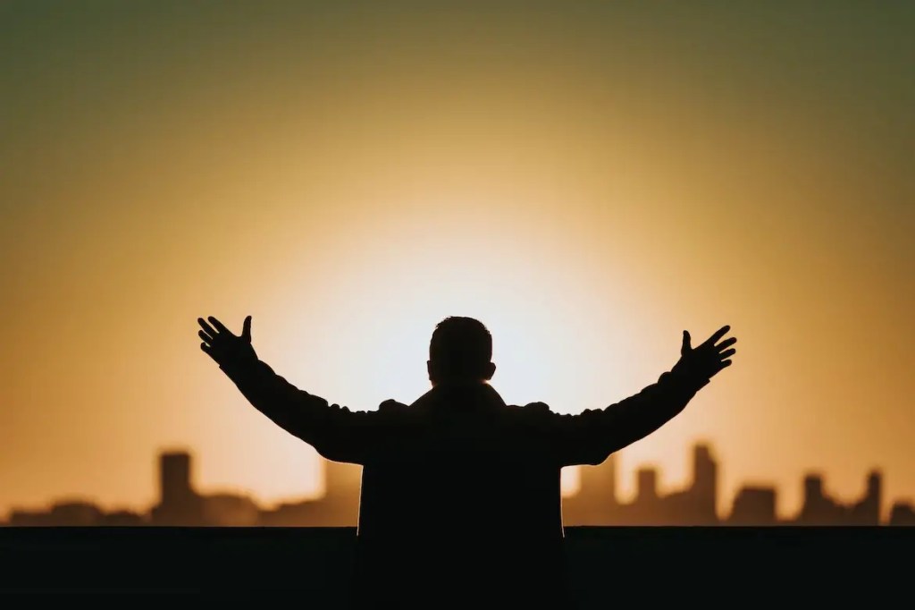 man raising his hands in prayer and worship to God