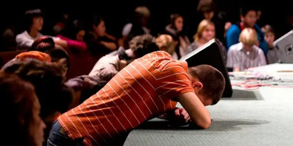 what is altar call a man praying on the side of a church stage