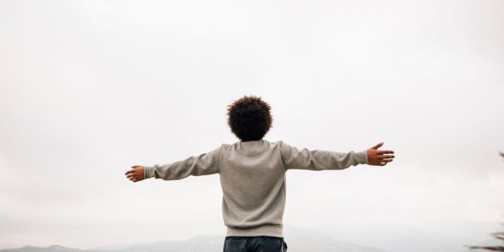 a kid with his arms wide open looking up with hope