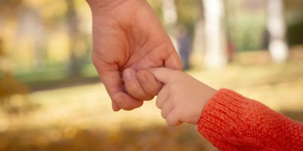 a hand of a parent and child walking together