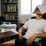 person sitting in front of the desk with a notebook on his face